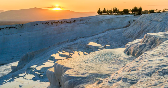 土耳其棉堡（Pamukkale）白色石灰岩梯田與溫泉池在夕陽下的壯麗景色